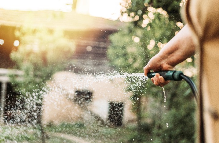 Hand hält Gartenschlauch mit Wasser